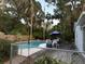 Backyard pool area with a wooden deck, complete with outdoor dining furniture and lush greenery, perfect for entertaining at 4818 Huron St, Zephyrhills, FL 33541