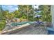 Backyard features an in-ground pool surrounded by lush landscaping and a dining set on a wooden deck at 4818 Huron St, Zephyrhills, FL 33541