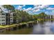 Exterior view of the condo buildings, showcasing the lake, fountain, balconies, and mature trees at 5980 80Th N St # 408, St Petersburg, FL 33709