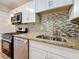 Close up of the kitchen area featuring granite counters, stainless appliances and mosaic backsplash at 5980 80Th N St # 408, St Petersburg, FL 33709