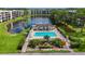 Community pool with lounge chairs surrounded by a black fence, lush landscaping, and beautiful lake views at 5980 80Th N St # 408, St Petersburg, FL 33709