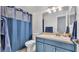 A cozy bathroom featuring a single sink vanity with blue cabinets and a shower with matching blue curtains at 3911 Smoke Rise Ct, Valrico, FL 33594
