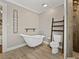 Relaxing bathroom with a clawfoot tub, wooden shelves, and modern shower with wood-look tile at 2802 Midway Rd, Plant City, FL 33565