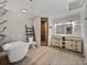 Elegant bathroom featuring a clawfoot tub, dual vanity, wooden shelves, and tiled shower at 2802 Midway Rd, Plant City, FL 33565