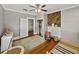 Bright bedroom with hardwood floors, a ceiling fan, closet, and a decorative wood paneled wall behind a white fireplace at 2802 Midway Rd, Plant City, FL 33565