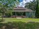 Charming home with a green exterior, front porch, and lush landscaping at 2802 Midway Rd, Plant City, FL 33565