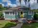 Charming home featuring a welcoming front porch, a vibrant yellow door, and lush green landscaping at 2802 Midway Rd, Plant City, FL 33565