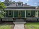 Charming home featuring a welcoming front porch, a vibrant yellow door, and lush green landscaping at 2802 Midway Rd, Plant City, FL 33565