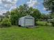 Detached storage shed in backyard; ideal for tools and equipment, surrounded by green lawn and shady trees at 2802 Midway Rd, Plant City, FL 33565