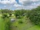 Aerial view showcasing a large backyard with mature trees, a chicken coop, and ample green space at 2802 Midway Rd, Plant City, FL 33565
