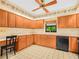Well-equipped kitchen with wooden cabinets, tiled floor, and modern appliances with a window above the sink at 2815 Kebs Ln, Plant City, FL 33565