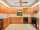 Efficient kitchen layout with wooden cabinets, black appliances, and a decorative ceiling fan at 2815 Kebs Ln, Plant City, FL 33565
