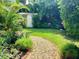Lush backyard featuring a stone pathway, green grass, mature trees, and a shed for extra storage at 4718 Crystal Ave, Sarasota, FL 34231