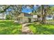 Exterior of the house showing the walkway and outdoor area with grass and large oak trees at 1309 Joe Mcintosh Rd, Plant City, FL 33565