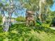 Wooden playhouse with slide and swing set in a lush, shaded backyard at 173 Portland Ave, Spring Hill, FL 34606
