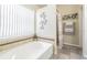 Bright bathroom featuring a soaking tub, decorative wall art, and tiled shower with neutral color palette at 4223 Amber Ridge Ln, Valrico, FL 33594