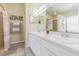 Bathroom featuring double sinks with white cabinets, a large mirror, and tiled shower, providing a functional space at 4223 Amber Ridge Ln, Valrico, FL 33594