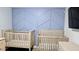 Bedroom design with two baby cribs, modern geometric wall art, and contemporary furnishings at 4592 Crabapple Ave, North Port, FL 34287
