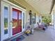 Charming front porch with rocking chairs, rustic decor, and a welcoming red door, creating a cozy entrance at 4611 Executive Meadows Dr, Plant City, FL 33567