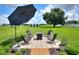 Outdoor patio featuring stylish seating, a fire pit, and an umbrella for shade in a landscaped backyard at 4616 Edwards Rd, Plant City, FL 33567