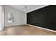 Minimalist bedroom with black accent wall, ceiling fan, and wood flooring at 8050 Eacon Ct, Hudson, FL 34667