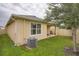 Residential backyard with grassy area, trees, fence, and patio with sliding glass doors at 32668 Abby Lax Ln, Wesley Chapel, FL 33543