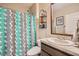 Well-lit bathroom with shower, patterned curtain, vanity and decorative shelving at 32668 Abby Lax Ln, Wesley Chapel, FL 33543