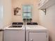 Functional laundry room with modern washer, dryer and decorative plant accents at 32668 Abby Lax Ln, Wesley Chapel, FL 33543