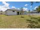 Wide backyard view of white home featuring a covered patio adjacent to a fenced pool in a neighboring yard at 3157 Bay City Ter, North Port, FL 34286