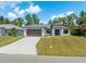 Lovely one-story home featuring a two-car garage, modern architectural details, and a spacious driveway surrounded by greenery at 3157 Bay City Ter, North Port, FL 34286