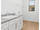 Clean laundry room with white cabinets, stainless steel faucet, a window, and an overhead shelf at 3157 Bay City Ter, North Port, FL 34286