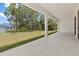 Spacious covered patio featuring views of the backyard with lush trees and a blue-roofed building at 3157 Bay City Ter, North Port, FL 34286