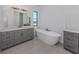 Modern bathroom with soaking tub, double vanity, and gray cabinets at 1729 Lugano Cir, Nokomis, FL 34275