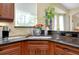 Kitchen featuring a bright window, granite countertops, custom cabinetry, and stainless steel sink at 11065 Barnsley Dr, Venice, FL 34293