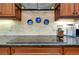 Kitchen cooktop with granite countertop and wood cabinets at 11065 Barnsley Dr, Venice, FL 34293