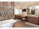 Luxury bathroom featuring double vanity, soaking tub, and unique mirrored tile accent wall for modern elegance at 361 Benjamin Franklin Dr # A, Sarasota, FL 34236