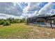 Spacious backyard with a view of the screened in in-ground pool and the home at 1061 Owl Dr, Englewood, FL 34223