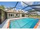 A bright blue inviting screened-in in-ground pool and back patio with an open view at 1061 Owl Dr, Englewood, FL 34223