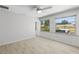Bright and neutral room with white walls, light wood floors, and large windows overlooking the backyard at 566 Viridian St, Englewood, FL 34223