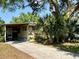 Tan mobile home with covered carport and mature landscaping at 5220 Palena Blvd, North Port, FL 34287