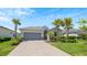 Single-story home with gray garage door, paver driveway, and lush landscaping at 15177 Spanish Point Dr, Port Charlotte, FL 33981