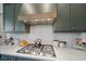 Modern gas cooktop with stainless steel range hood and white tile backsplash at 284 Bocelli Dr., Nokomis, FL 34275