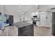 Bright kitchen features a large granite island, white cabinets, stainless steel appliances, and stylish pendant lighting at 13564 Wainwright Dr, Port Charlotte, FL 33953