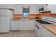 Compact kitchen featuring white cabinets, essential appliances, and a window view at 109 Lakeview Dr, North Port, FL 34287