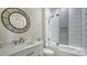 Modern bathroom featuring sleek vanity, a round mirror, and a glass-enclosed shower over tub combination at 334 Melrose Ct, Venice, FL 34292