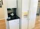 Convenient kitchenette area with white cabinets, black countertops, and a refrigerator with water dispenser at 334 Melrose Ct, Venice, FL 34292