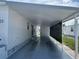 Covered carport area with privacy wall and concrete flooring at 923 Cortina Blvd, Venice, FL 34285