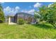 Backyard view of home with screened lanai, lush green lawn, and surrounding trees at 233 Fairway Rd, Rotonda West, FL 33947