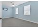 Bedroom with light blue walls, carpet floors, ceiling fan, and two windows at 233 Fairway Rd, Rotonda West, FL 33947