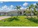 Charming home with a well-manicured front lawn, mature palm trees, and a spacious two-car garage at 233 Fairway Rd, Rotonda West, FL 33947